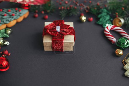 Téléchargez les photos : Joyeux Noël et Joyeuses Fêtes ! Cadeau de Noël élégant et branches, baies rouges, ornements en or cadre sur fond noir. Carte de voeux de la saison, vacances d'hiver - en image libre de droit