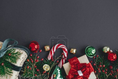 Téléchargez les photos : Appartement de Noël moderne laïc. Cadeaux de Noël élégants, branches d'arbre, canne à bonbons, décorations festives bordent sur fond noir. Bannière des vacances d'hiver. Joyeux Noël et Joyeuses Fêtes - en image libre de droit