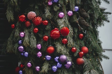 Foto de Elegantes ramas de abeto de Navidad con muchas bolas de colores en el exterior del edificio. Decoración moderna de Navidad en la calle de la ciudad. Vacaciones de invierno en Europa. Feliz Navidad. - Imagen libre de derechos
