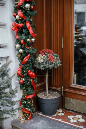 Téléchargez les photos : Élégant sapin de Noël et branches de sapin avec des boules sur le bâtiment extérieur. Décor de Noël moderne dans la rue de la ville. Vacances d'hiver en Europe. Joyeux Noël - en image libre de droit