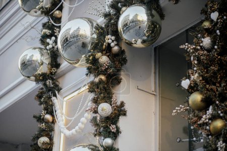 Photo for Stylish christmas silver and gold baubles and fir branches on building exterior. Modern christmas decor in city street. Winter holidays in Europe. Merry Christmas - Royalty Free Image
