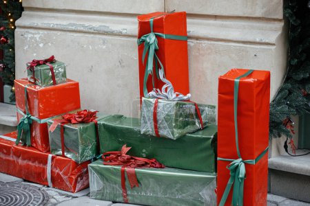 Photo for Stylish red and green wrapped christmas gifts and presents at  building exterior. Modern christmas decor in city street. Winter holidays in Europe. Festive decorations - Royalty Free Image