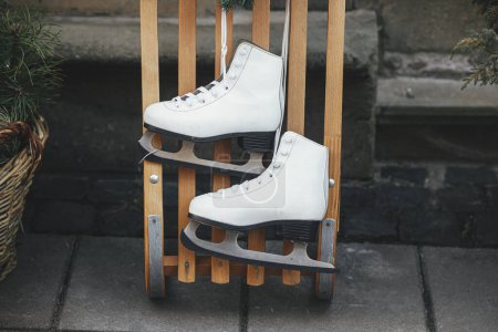 Téléchargez les photos : Élégants patins à glace vintage et traîneau en bois à l'extérieur du bâtiment. Décor de Noël moderne dans la rue de la ville. Vacances d'hiver en Europe. Joyeux Noël - en image libre de droit