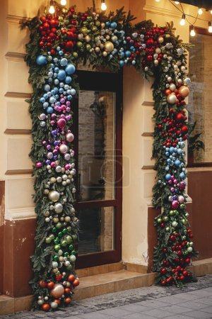 Téléchargez les photos : Branches élégantes de sapin de Noël avec de nombreuses boules colorées sur l'extérieur du bâtiment. Décor de Noël moderne dans la rue de la ville. Vacances d'hiver en Europe. Joyeux Noël - en image libre de droit