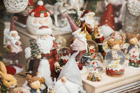 Téléchargez les photos : Souvenirs de Noël élégants, clauses de Père Noël, boules à neige, jouets bonhomme de neige dans la vitrine du magasin festif. Décor de Noël moderne dans la rue de la ville. Vacances d'hiver en Europe. Joyeux Noël - en image libre de droit