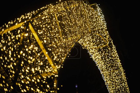 Foto de Las luces de oro de Navidad con estilo en la plaza de la ciudad por la noche, la iluminación festiva bokeh. Decoración moderna de Navidad en la calle de la ciudad. Vacaciones de invierno atmosféricas. Feliz Navidad y Felices Fiestas! - Imagen libre de derechos