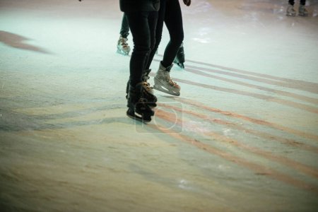 Téléchargez les photos : Patineurs sur patinoire, patins rapprochés. Les gens qui s'amusent et patinent sur la place de la ville en soirée.Jambes avec patineurs sur glace vue recadrée. Vacances d'hiver atmosphériques en Europe. Joyeuses fêtes! - en image libre de droit