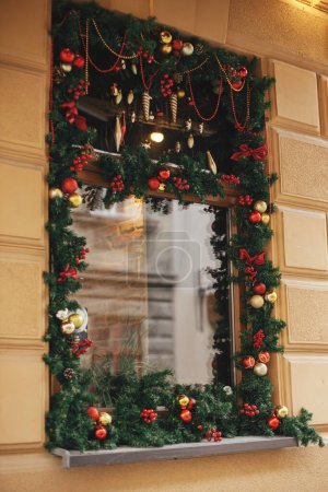Téléchargez les photos : Élégante arche de Noël avec des boules rouges et dorées accrochées sur des branches de sapin à l'extérieur du bâtiment. Décor de Noël moderne dans la rue de la ville. Vacances d'hiver en Europe. Joyeux Noël - en image libre de droit