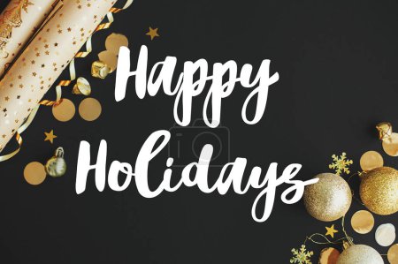 Frohes Neues Jahr Textschild auf moderner Weihnachtsflache, goldenes Geschenkpapier, Christbaumkugeln, Konfetti auf schwarzem Hintergrund. Grußkarte der Saison