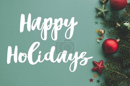 Photo for Happy Holidays text sign on christmas border with festive decorations, confetti, fir branches on green background flat lay. Season's greeting card. Christmas postcard - Royalty Free Image
