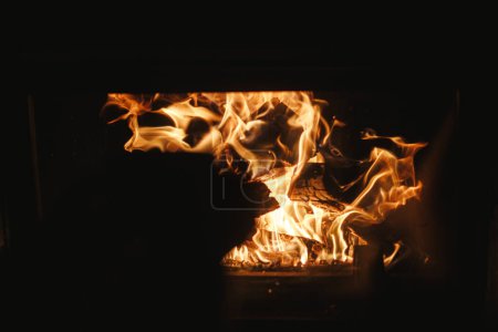 Photo for Close up of burning wood in fireplace in dark evening room. Fireplace heating in house, electricity blackout. Atmospheric time at fireside in home - Royalty Free Image