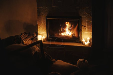 Photo for Cozy burning fireplace and candles in dark evening room. Fireplace heating in house, electricity blackout. Atmospheric time at fireside in home - Royalty Free Image