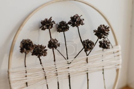 Photo for Stylish boho autumn wreath with dry flowers. Wooden hoop, thread and dry herbs on white wall background. Modern floral arrangement and creative handmade decor - Royalty Free Image