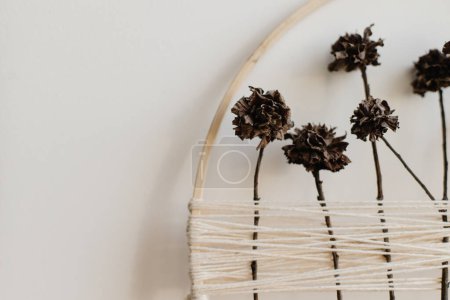 Photo for Stylish boho autumn wreath with dry flowers. Wooden hoop, thread and dry herbs on white wall background. Modern floral arrangement and creative handmade decor - Royalty Free Image