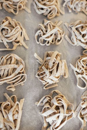 Photo for Homemade pasta. Dry fettuccine noodles in nests on baking tray close up. Making whole-grain pasta in kitchen, home made italian dinner - Royalty Free Image