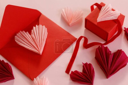 Foto de Happy Valentine's day! Stylish pink hearts, red envelope, gift box on pink paper background. Modern Valentines day composition. Love letter concept - Imagen libre de derechos