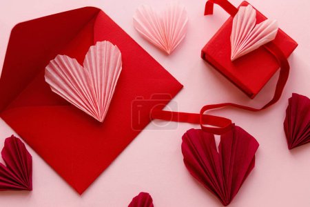Téléchargez les photos : Happy Valentine's day! Stylish pink hearts, red envelope, gift box flat lay on pink paper background. Modern Valentines day composition. Love letter concept - en image libre de droit