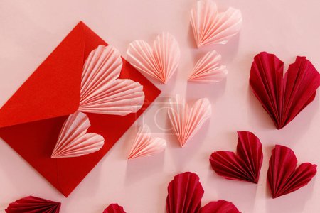 Téléchargez les photos : Stylish pink hearts and red envelope flat lay on pink paper background. Happy Valentine's day! Modern Valentines day composition. Love letter concept. - en image libre de droit