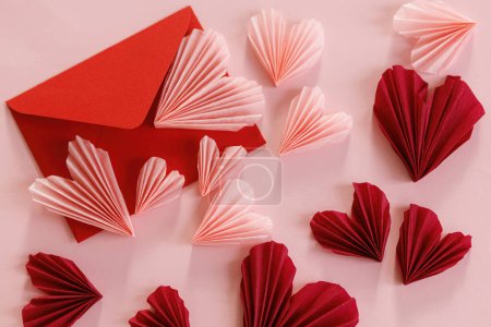 Téléchargez les photos : Valentines day flat lay. Stylish red envelope with pink and red hearts composition on pink paper background. Creative modern valentines hearts cutouts. Love letter. Happy Valentine's day - en image libre de droit
