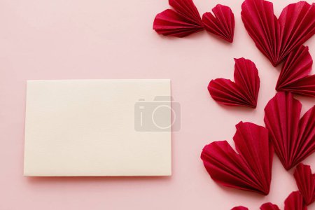 Téléchargez les photos : Happy Valentine's day! Empty card and stylish red hearts flat lay on pink paper background. Creative modern valentines greeting card mock up with space for text. Love letter - en image libre de droit