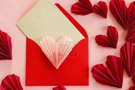 Téléchargez les photos : Happy Valentine's day! Stylish envelope with pink and red hearts flat lay on pink paper background. Creative modern valentine hearts cutouts. Love letter, space for text - en image libre de droit
