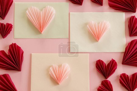 Téléchargez les photos : Happy Valentine's day! Stylish envelopes with pink and red hearts flat lay on pink paper background. Modern valentine hearts cutouts. Love letter. Creative composition - en image libre de droit