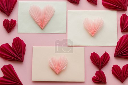 Photo for Valentines day flat lay. Stylish envelope with pink and red hearts composition on pink paper background. Creative modern valentine hearts cutouts. Happy Valentine's day! Love letter - Royalty Free Image