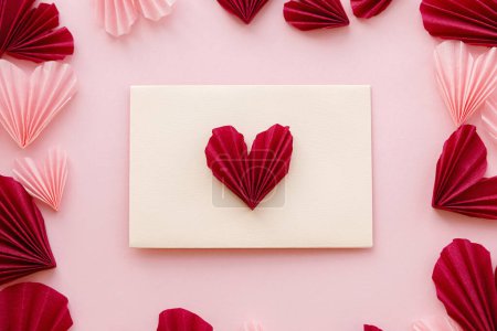 Téléchargez les photos : Valentines day flat lay. Stylish envelope with pink and red hearts composition on pink paper background. Creative modern valentine hearts cutouts. Happy Valentine's day! Love letter - en image libre de droit