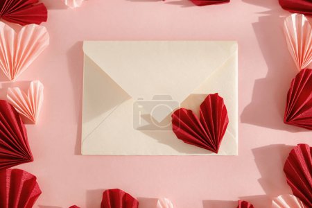 Téléchargez les photos : Happy Valentine's day! Stylish envelope with pink and red hearts flat lay on pink paper background. Modern valentine heart cutouts. Love letter, space for text. Creative composition - en image libre de droit