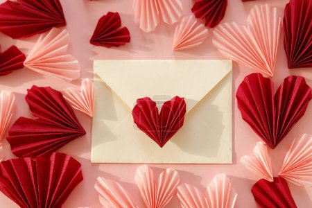 Téléchargez les photos : Happy Valentine's day! Stylish envelope with pink and red hearts flat lay on pink paper background. Modern valentine heart cutouts. Love letter. Creative composition - en image libre de droit