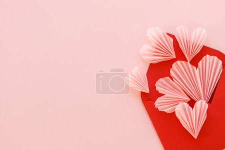 Téléchargez les photos : Happy Valentine's day! Stylish red envelope with pink hearts flat lay on pink paper background. Modern valentine heart cutouts. Love banner, space for text. Creative letter composition - en image libre de droit