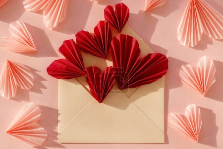Téléchargez les photos : Happy Valentine's day! Stylish envelope with red and pink hearts flat lay on pink paper background. Modern valentine card with heart cutouts. Love letter. Creative composition - en image libre de droit