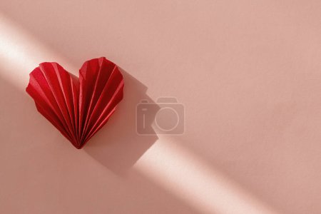 Téléchargez les photos : Happy Valentine's day! Stylish red heart in sunlight on pink paper background flat lay. Modern cute valentine heart cutout, space for text. Creative love banner - en image libre de droit