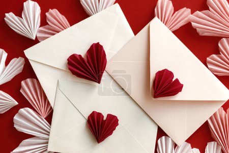 Téléchargez les photos : Valentines day flat lay. Stylish envelopes with pink and red hearts composition on red paper background. Creative modern valentine hearts cutouts. Happy Valentine's day! Love letter - en image libre de droit