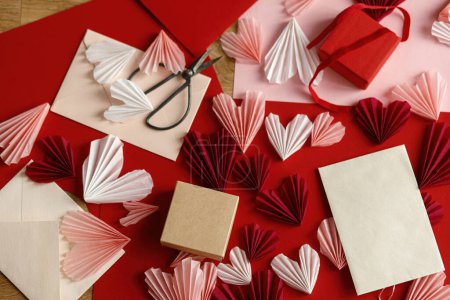 Foto de Happy Valentine's day! Stylish empty card, gift box, red and pink hearts, scissors, paper on wooden table top view. Valentine day holiday preparations. Modern creative love letter mock up - Imagen libre de derechos