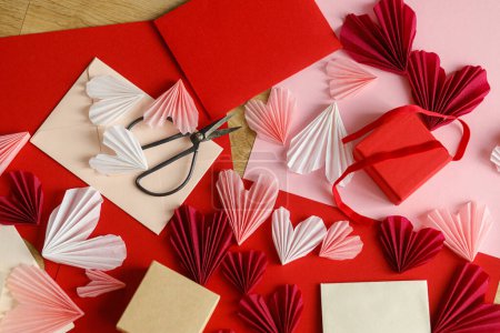 Foto de Stylish envelope with red and pink hearts, scissors, gift box and paper on wooden table top view. Valentine day holiday preparations. Modern creative love letter. Happy Valentine's day! - Imagen libre de derechos