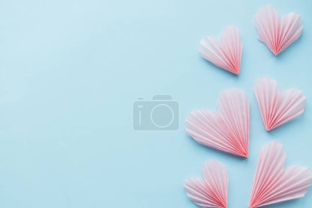 Téléchargez les photos : Happy Valentine's day! Stylish pink hearts on blue paper background flat lay. Modern cute valentine heart cutouts composition with space for text. Creative love banner - en image libre de droit