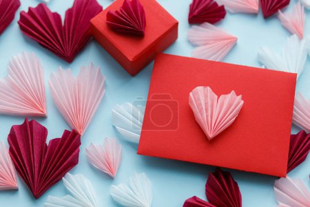 Téléchargez les photos : Happy Valentine's day! Stylish red envelope, gift, pink and red hearts composition on blue paper background. Creative modern valentine hearts cutouts. Love letter - en image libre de droit