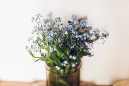 Photo for Beautiful blue spring little flowers on rustic background in room. Delicate myosotis petals, forget me not. Simple countryside living, home decor - Royalty Free Image