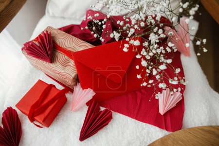 Photo for Happy valentines day! Modern gifts, red envelope, hearts and white flowers on cozy armchair. Valentine morning surprise. Valentines day gift - Royalty Free Image