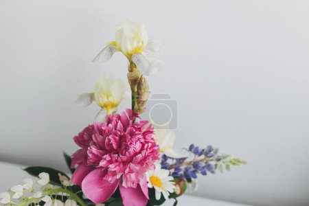 Photo for Modern summer flowers still life arrangement on white wall background with space for text. Creative floral greeting card. Stylish peony, lupin, iris and daisy composition - Royalty Free Image