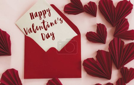 Téléchargez les photos : Happy valentines day text on card and stylish red hearts flat lay on pink paper background. Modern Valentines day greeting card. Handwritten sign, love letter - en image libre de droit