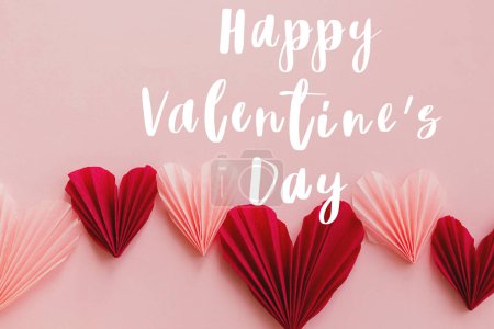 Téléchargez les photos : Happy valentines day text on cute red and pink hearts flat lay on pink paper background. Modern Valentines day greeting card. Handwritten sign - en image libre de droit