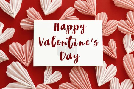 Téléchargez les photos : Happy valentines day text on card and stylish red and pink hearts flat lay on red paper background. Modern Valentines day greeting card. Handwritten sign - en image libre de droit