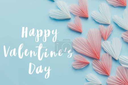 Téléchargez les photos : Happy valentines day text on cute pink hearts on blue paper background flat lay. Modern Valentines day greeting card. Handwritten sign. Hearts border - en image libre de droit
