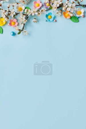 Téléchargez les photos : Stylish colorful candy flowers and cherry blossoms flat lay on blue background with copy space. Happy Easter! Greeting card template or modern holiday banner. Happy Mothers day - en image libre de droit