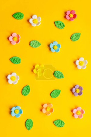 Photo for Stylish colorful flowers flat lay on yellow background. Modern festive holiday banner. Spring composition. Happy Easter! Sweet candy flowers and leaves. Greeting card - Royalty Free Image
