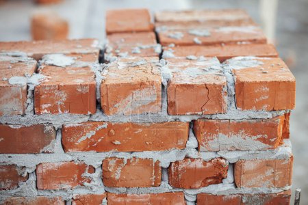 Photo for Bricks masonry with cement on concrete foundation close up, process of house building. Red bricks for laying on concrete foundation. Building materials at construction site - Royalty Free Image