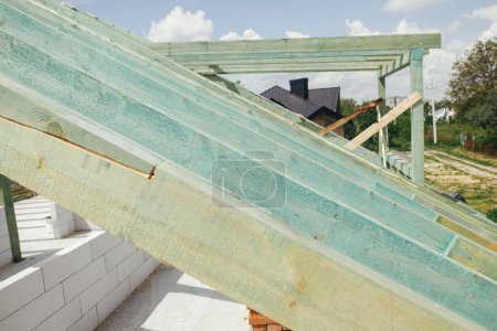 Photo for Unfinished roof trusses, view in attic with rafters and beams against sky. Wooden roof framing. Mansard of modern farmhouse building construction. - Royalty Free Image
