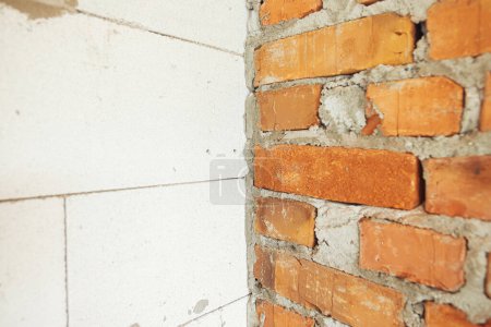 Foto de Masonry autoclaved aerated concrete blocks and bricks on concrete foundation. Laying walls with white blocks. Process of house building at construction site - Imagen libre de derechos